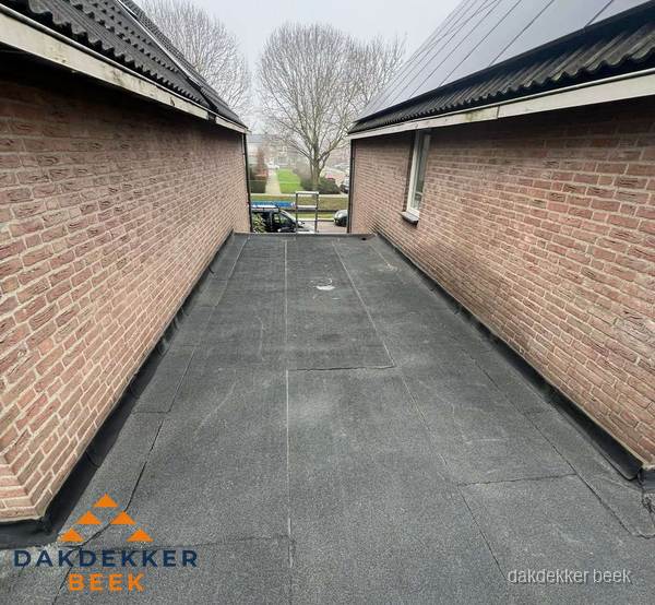 Plat dak met bitumen dakbedekking tussen bakstenen muren in Beek Plat dak met bitumen dakbedekking tussen bakstenen muren in Beek