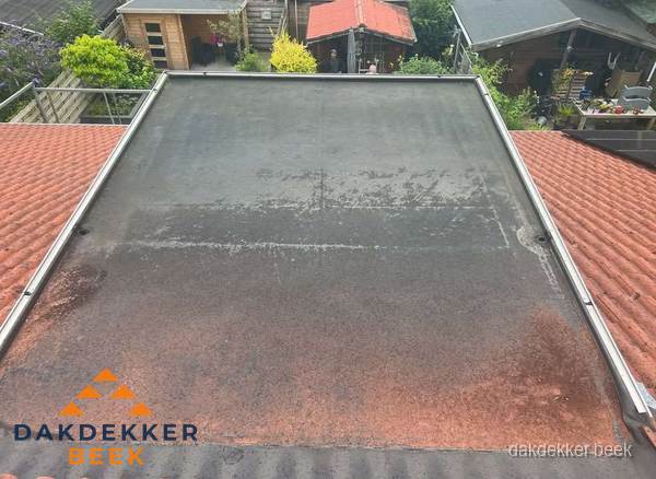 Verouderd plat dak met slijtage tussen schuine daken in Beek Verouderd plat dak met slijtage tussen schuine daken in Beek