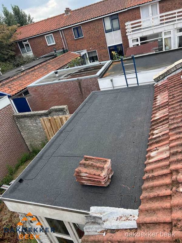 Plat dak aanbouw met bitumen naast schuin pannendak in Beek